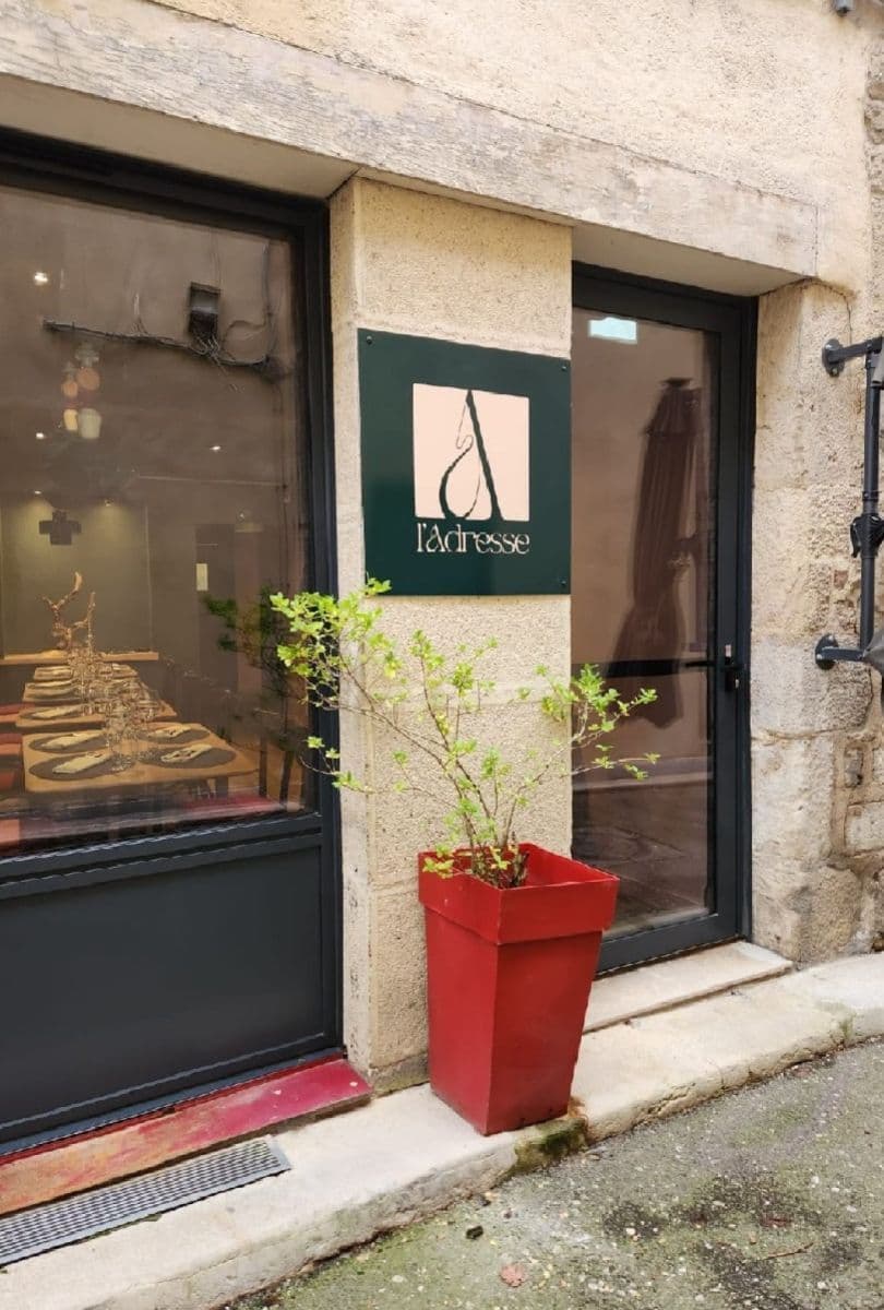 L'entrée du restaurant et son enseigne, pot de fleurs rouge devant la porte
